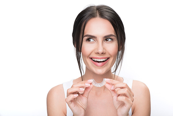Smiling woman with an Invisalign clear aligner.