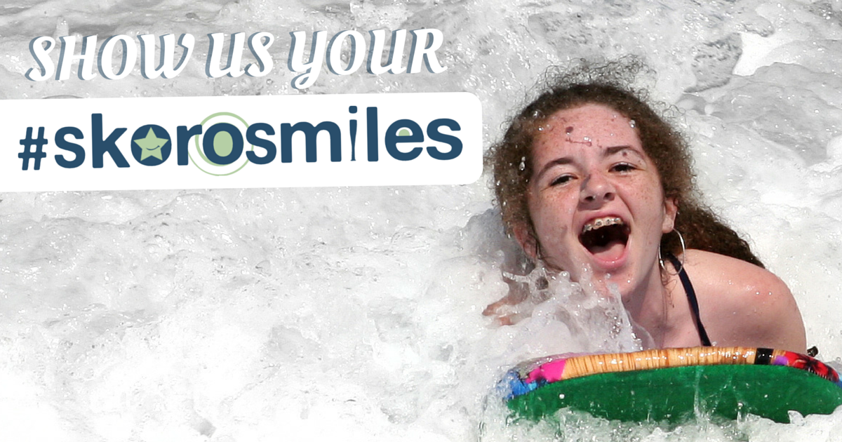 A young girl with braces having a great time boogie boarding at the beach.