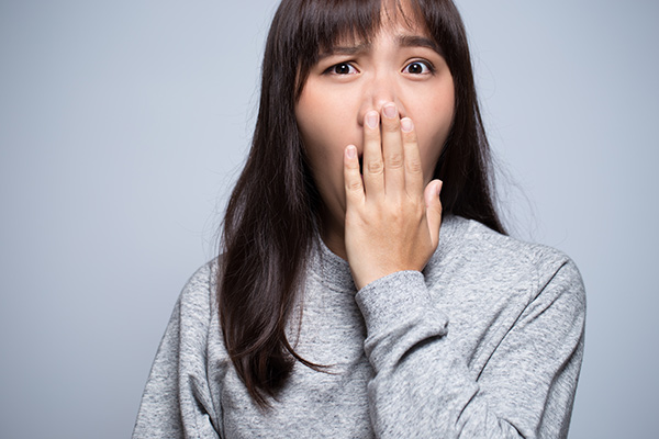 Woman with bad breath covering her mouth.