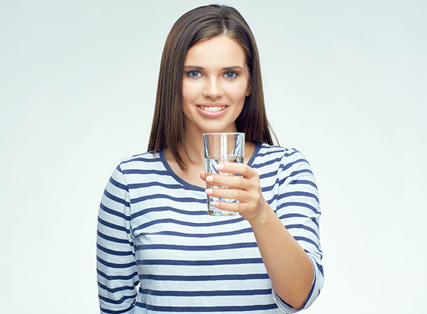 Young woman drinking water for dry mouth with braces.