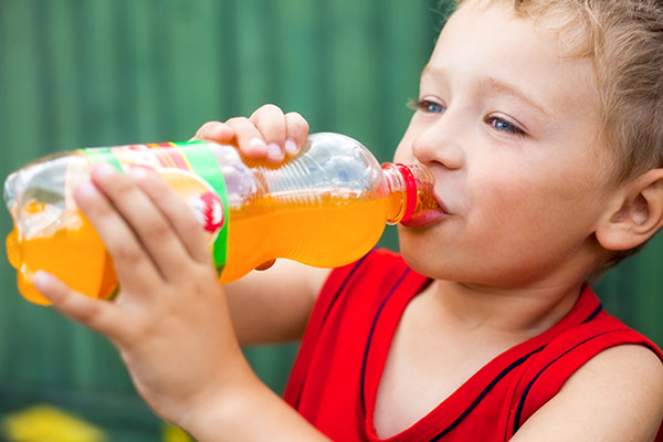 A child with bad dental habits drinking a sugary soda.