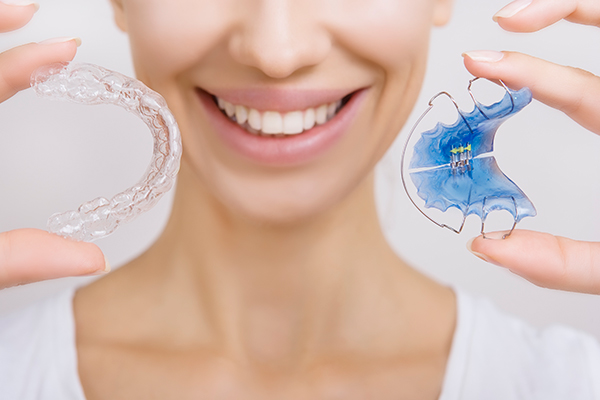 Woman holding two types of retainers for use after braces