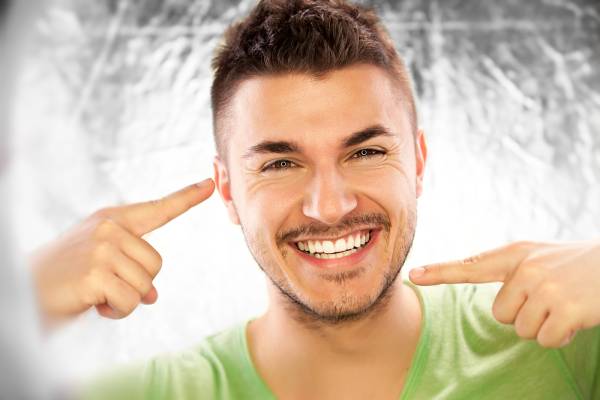 A man pointing to this teeth enjoying good oral health